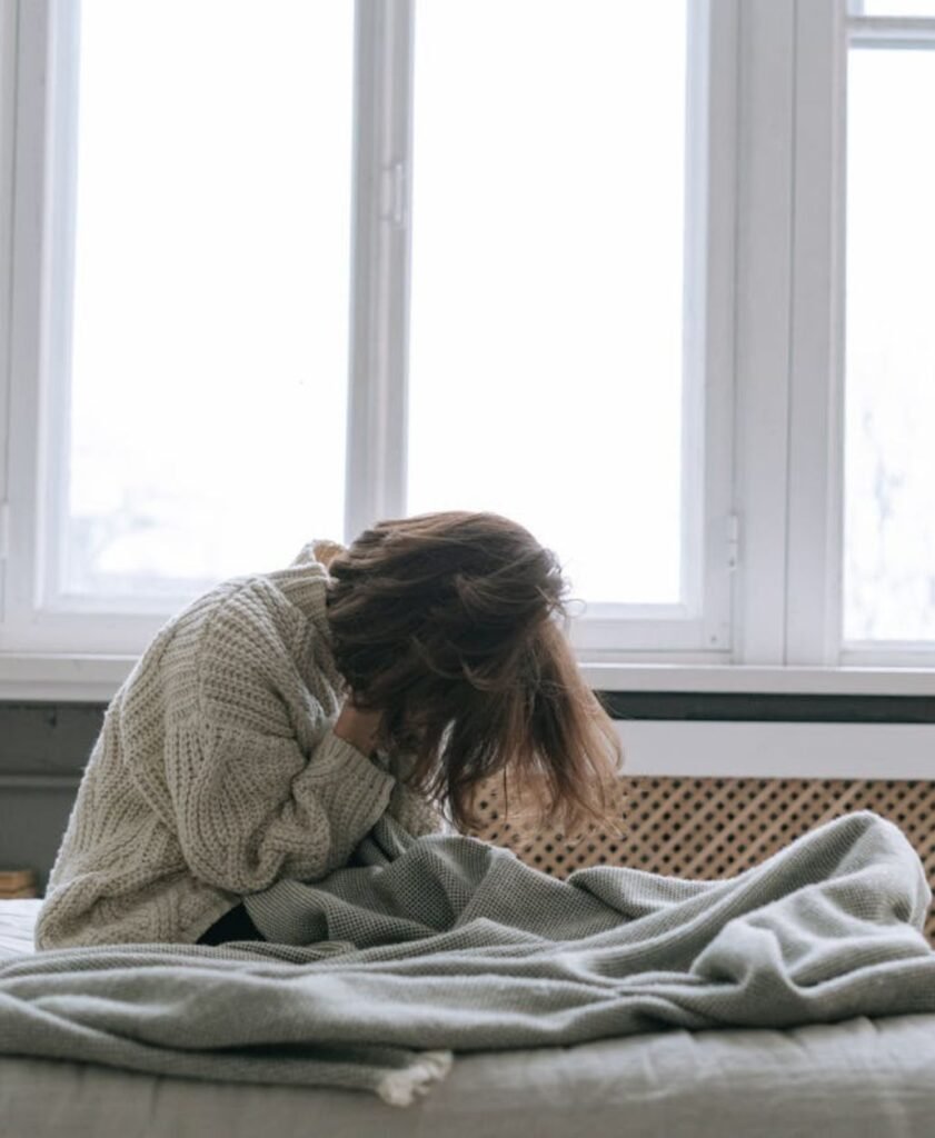 Person sitting on a bed with head bowed, reflecting emotional heaviness and personal growth