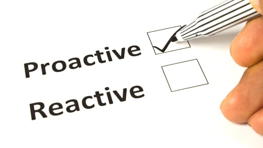 Photograph showing a close-up of a checklist with two options: "Proactive" and "Reactive." A hand holding a striped pen is marking a check in the box next to "Proactive," emphasizing a choice or preference for proactive behavior.