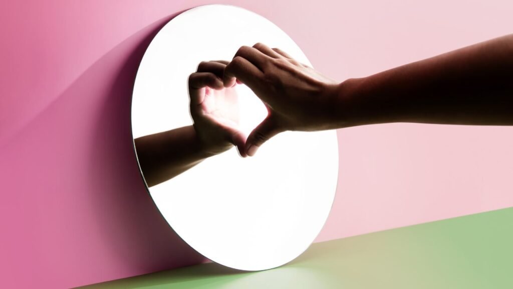 Hands forming a heart shape in a mirror, reflecting self-love and growing self-trust