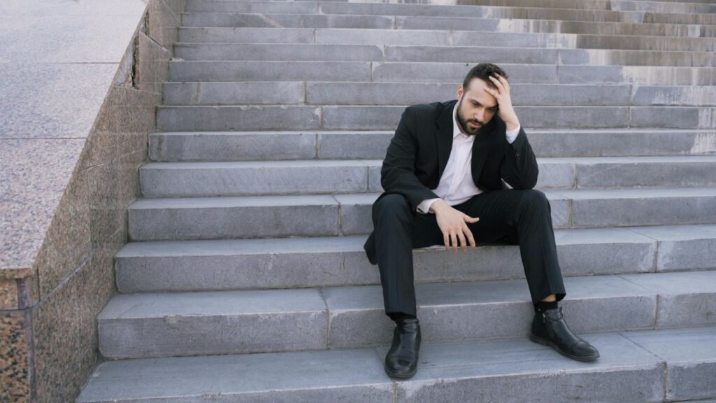 Man in business suit sitting on stairs looking stressed and deep in thought