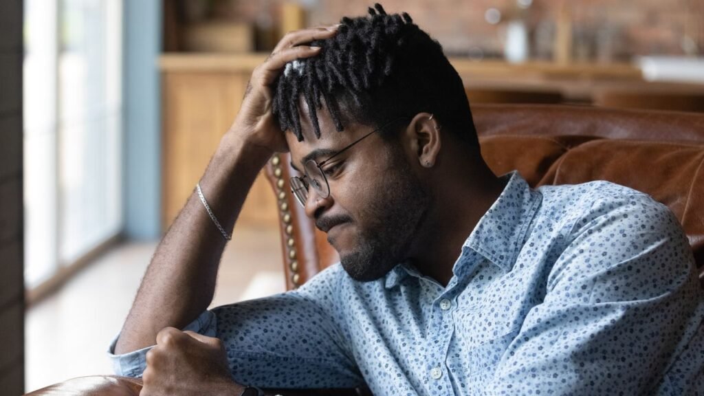 Man sitting on a chair looking stressed and thoughtful, highlighting the benefits of slowing down