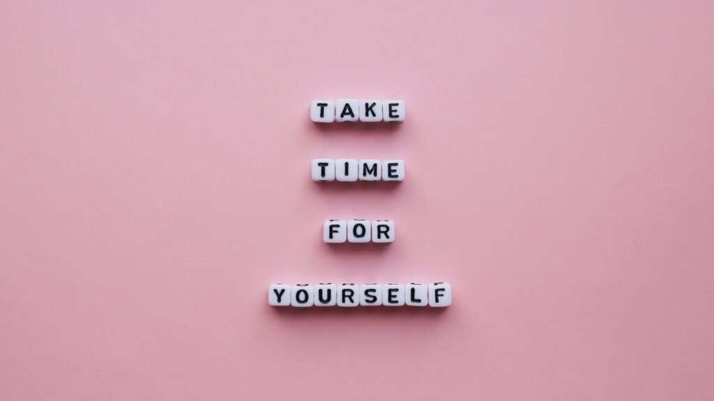 Minimalist pink background with “Take time for yourself” spelled in tiles, encouraging self-trust and care