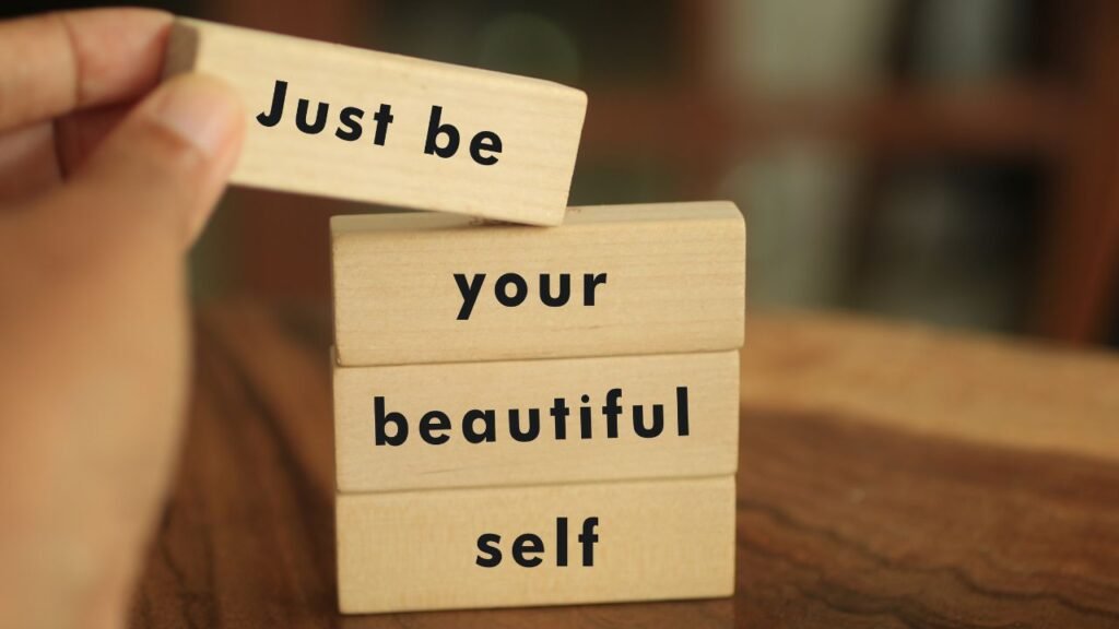 Stacked wooden blocks reading “Just be your beautiful self,” promoting self-trust and self-acceptance