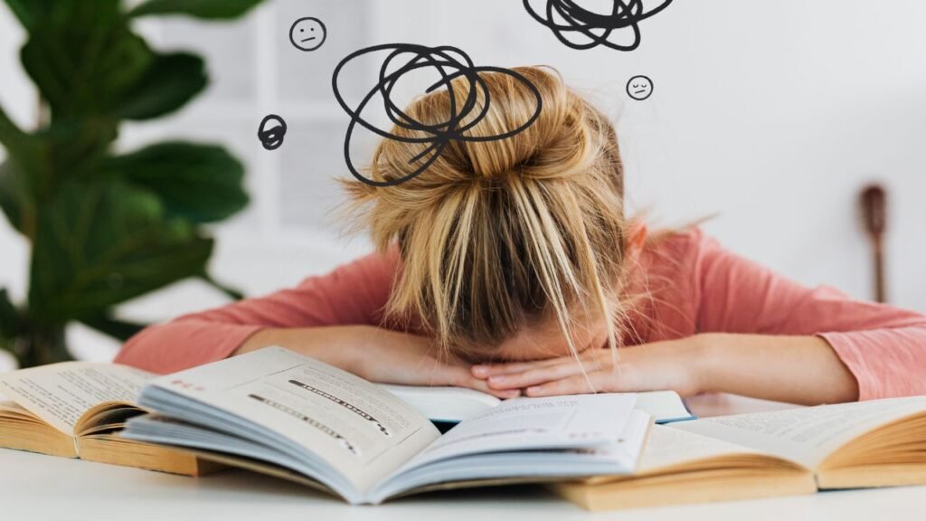 Stressed womant resting head on open books with doodles showing mental overwhelm