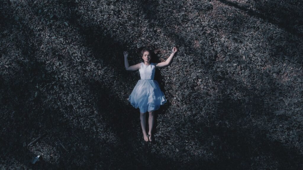 Woman lying on the ground in a calm outdoor setting, symbolizing rest and the benefits of slowing down
