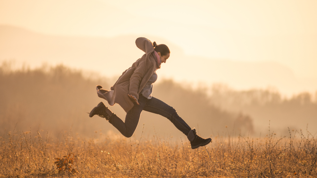 How to Start Choosing Yourself Without Losing Who You Are 4 Woman jumping freely in an open field at sunrise, symbolizing freedom and how to start choosing yourself with confidence