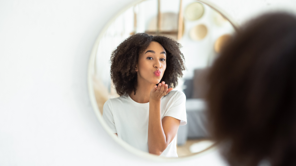 How to Start Choosing Yourself Without Losing Who You Are 3 Woman smiling at herself in the mirror, showing confidence and growth through how to start choosing yourself