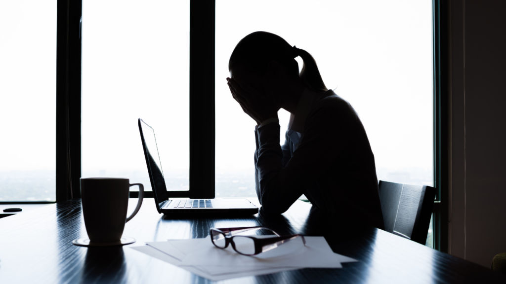 How to Let Go of Your Old Self Without Fear 2 Woman sitting at a desk in stress and reflection, representing how to let go of your old self and move toward personal growth