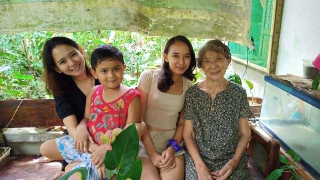 Ninety-Three Years of Love: What Lola Inay Taught Me About a Life Well Lived 4 Grandmother smiling with her grandchildren and great-grandchild while sitting together on a porch surrounded by lush greenery