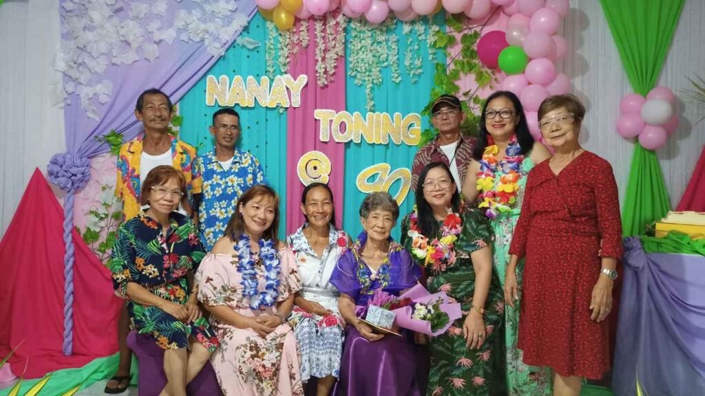 Ninety-Three Years of Love: What Lola Inay Taught Me About a Life Well Lived 5 Multi-generational family posing together at a colorful 90th birthday celebration with floral decorations and balloons