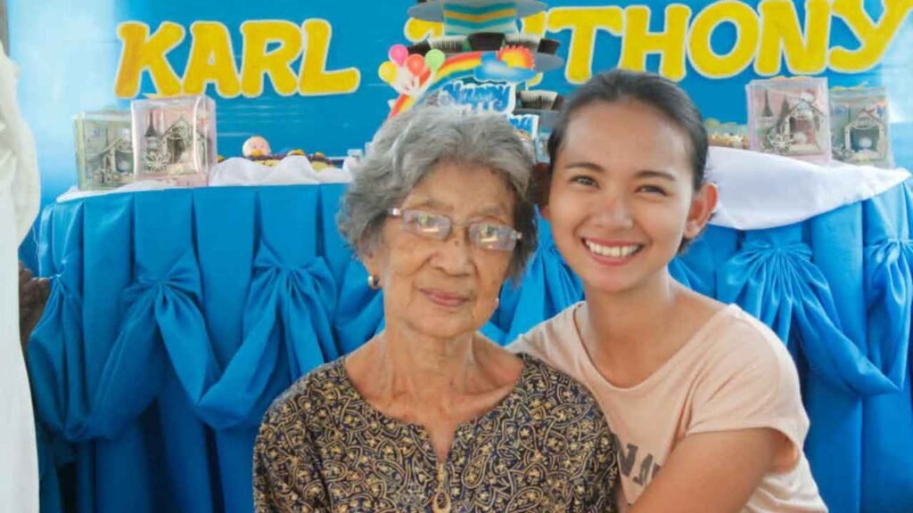 Ninety-Three Years of Love: What Lola Inay Taught Me About a Life Well Lived 10 Young woman smiling while embracing her elderly grandmother during a family christening celebration